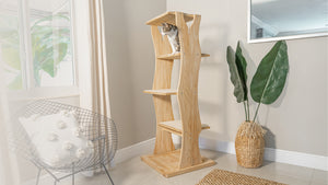 Brown and white tabby cat on a four-tiered wood cat tree shaped like a tree.